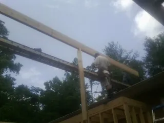 Carpenter setting a ridge beam over a new addition frame — Ice Dam Removal by Roofing Brothers in Ludington