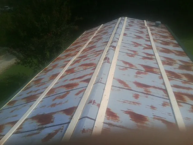 Rusted metal roof panels with new wood purlins before replacement — Storm Damage Roof Repair in Ludington by Roofing Brothers
