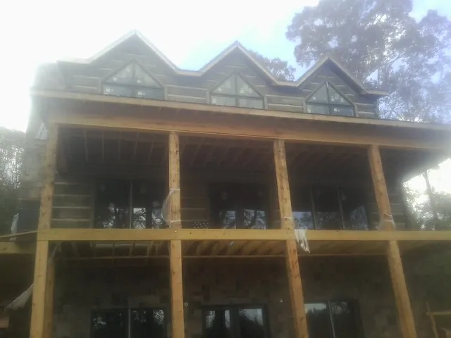 Dormers and porch framing on a large log home under construction — Roof Coating work by our crew in Ludington