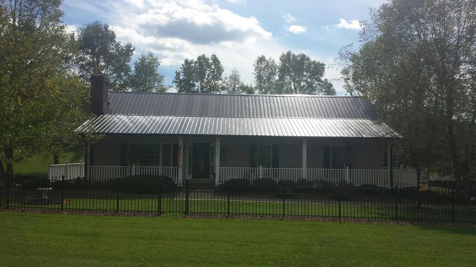 Gray metal roof on a brick ranch with a full width front porch — Gutter Guard Installation work by our crew in Ludington