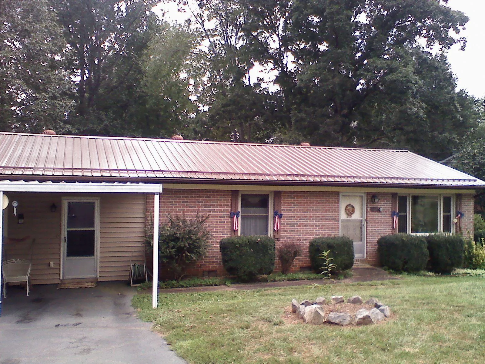 Bronze metal roof and carport on a brick ranch home — Roof Repair work by our crew in Ludington