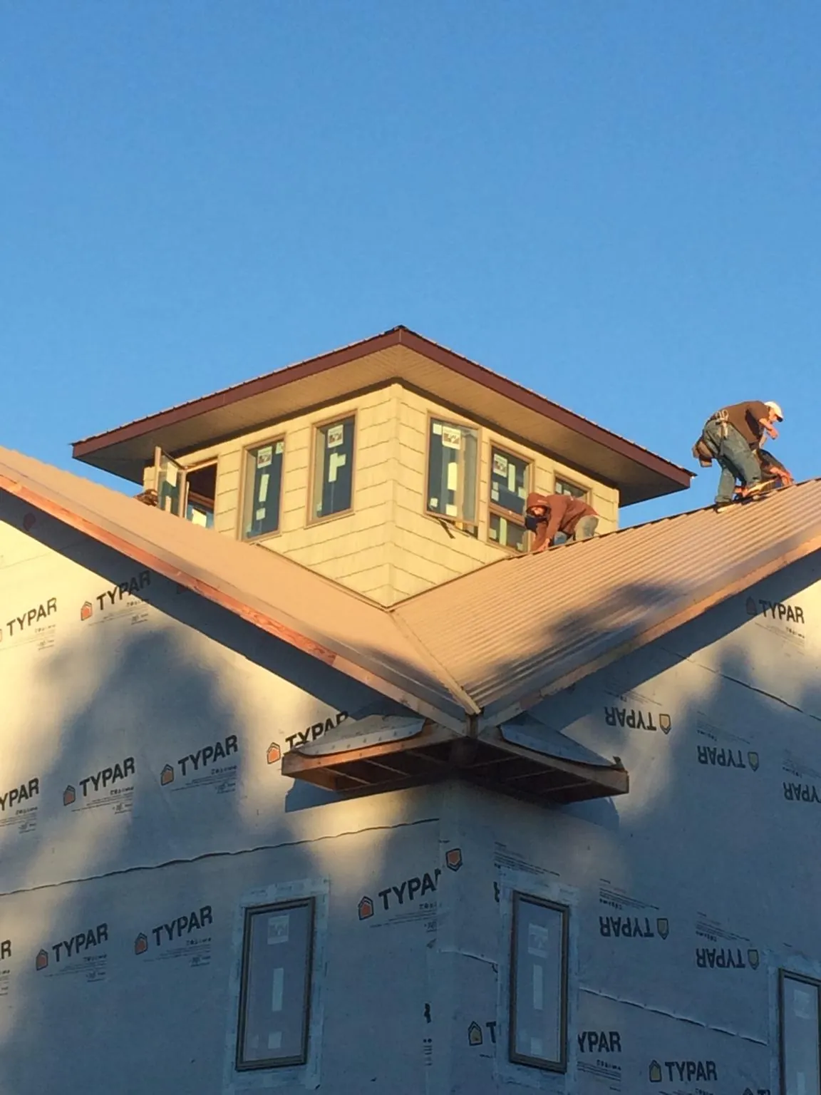 Roofers working around a rooftop cupola on a new metal roof at sunset — Roof Waterproofing in Ludington by Roofing Brothers